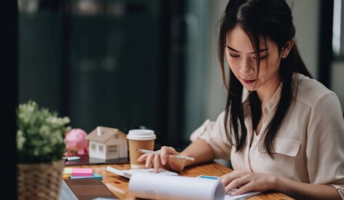 Woman looking at notepad and using calculator