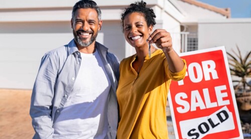 Couple In Front of For Sale:Sold Sign
