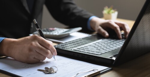 Person at Laptop Typing and Taking Notes for Real Estate Transaction